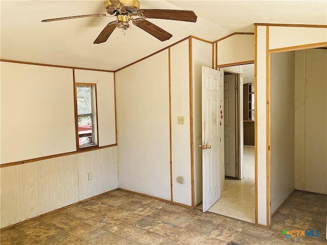 spare room with stone finish flooring, vaulted ceiling, and a ceiling fan
