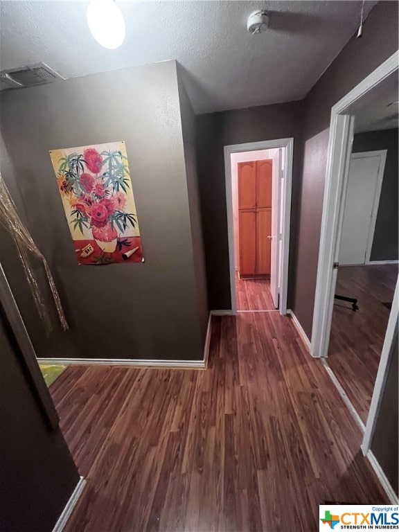 hallway with dark wood-type flooring and a textured ceiling