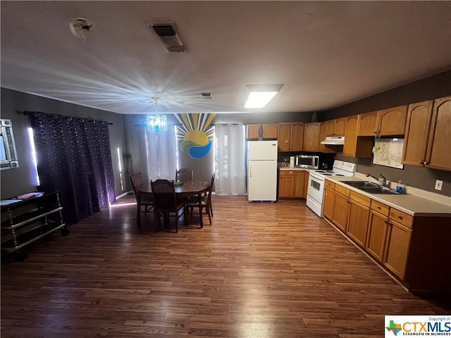 kitchen with a notable chandelier, white appliances, sink, and dark wood-type flooring