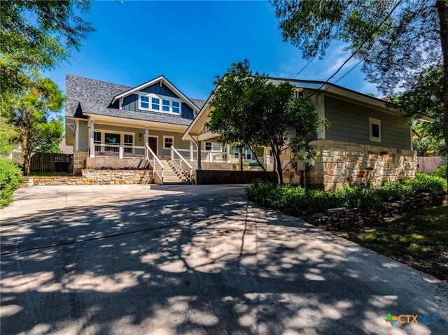 207 Yale St, San Marcos, TX 78666 - view of front of house with a porch, stone siding, board and batten siding, fence, and concrete driveway