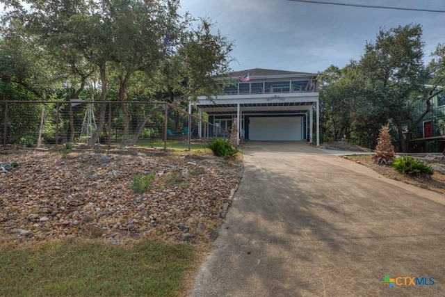 coastal home with an attached garage, driveway, and stairs