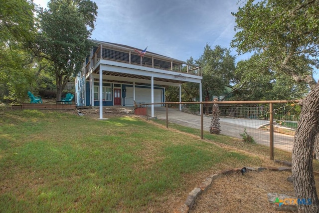 back of property featuring a lawn, driveway, a wooden deck, and a garage