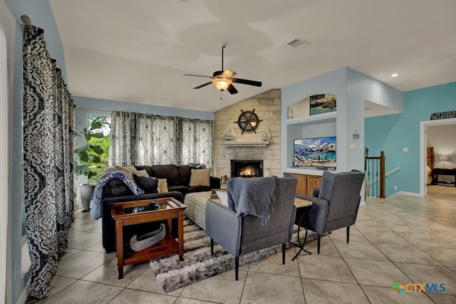 living room featuring lofted ceiling, a stone fireplace, visible vents, a ceiling fan, and light tile patterned flooring