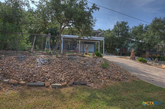 view of property hidden behind natural elements with concrete driveway