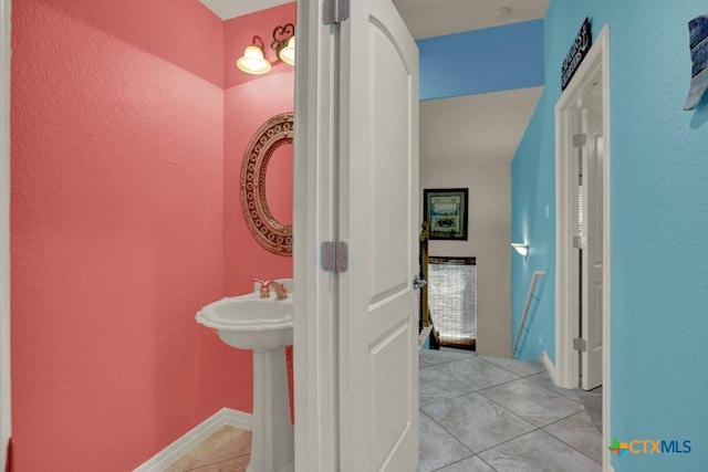 bathroom with a textured wall and tile patterned flooring