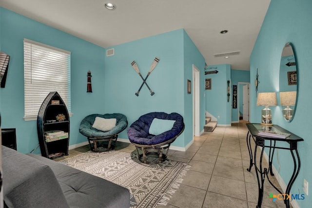 living area featuring baseboards, light tile patterned flooring, stairs, and visible vents