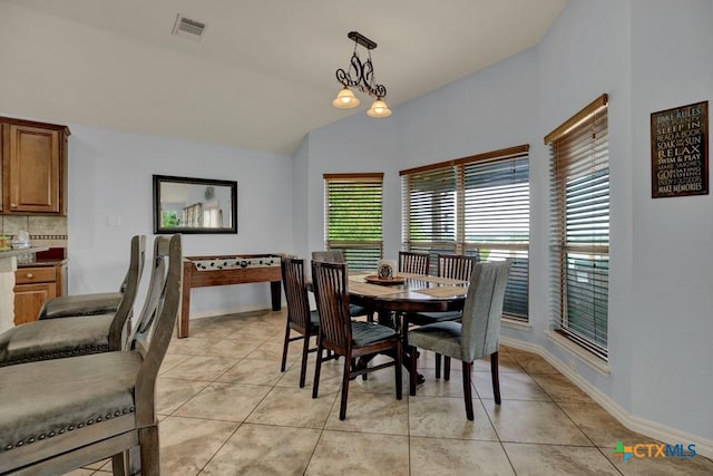 dining room featuring baseboards, lofted ceiling, visible vents, and light tile patterned floors