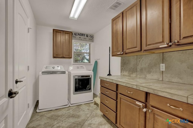 washroom with cabinet space, visible vents, washing machine and clothes dryer, and light tile patterned floors