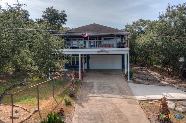view of front of house featuring a garage, concrete driveway, a balcony, and fence
