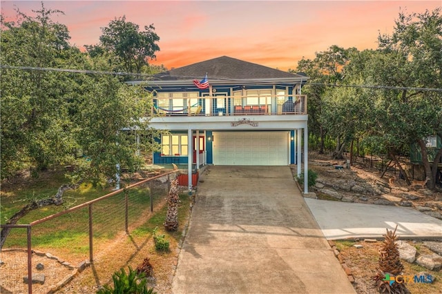 beach home with an attached garage, driveway, fence, and a balcony