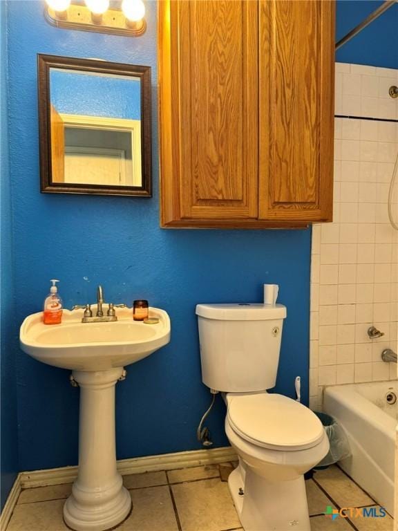 bathroom with tiled shower / bath, tile patterned floors, and toilet