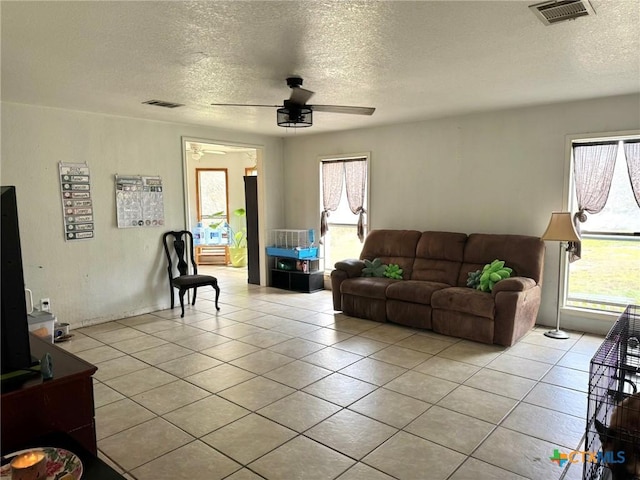 living room featuring light tile patterned floors, a textured ceiling, and ceiling fan