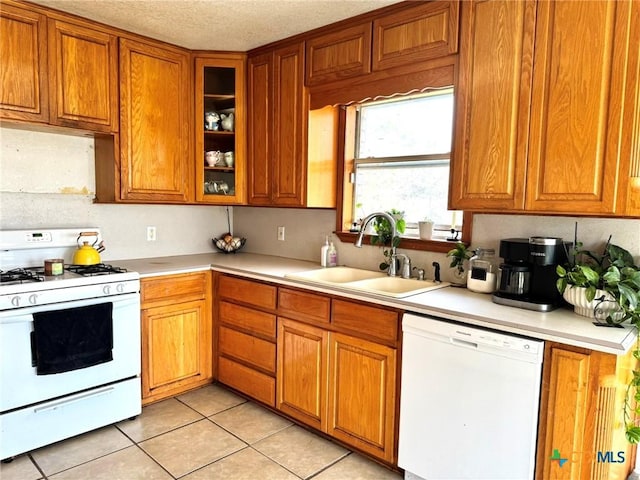 kitchen featuring light tile patterned flooring, white appliances, sink, and a textured ceiling