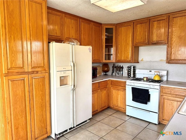 kitchen featuring light tile patterned flooring, a textured ceiling, and white appliances