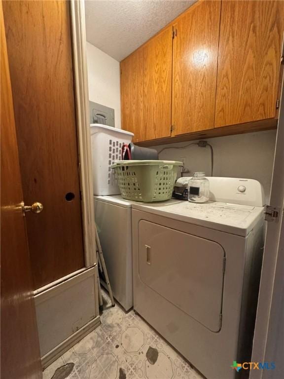 laundry room featuring cabinets, washer and dryer, and a textured ceiling