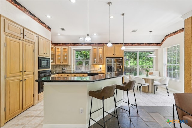 kitchen featuring black appliances, plenty of natural light, a breakfast bar area, dark countertops, and recessed lighting