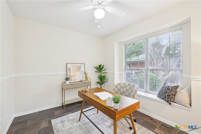 office area featuring stone tile floors, baseboards, and a ceiling fan