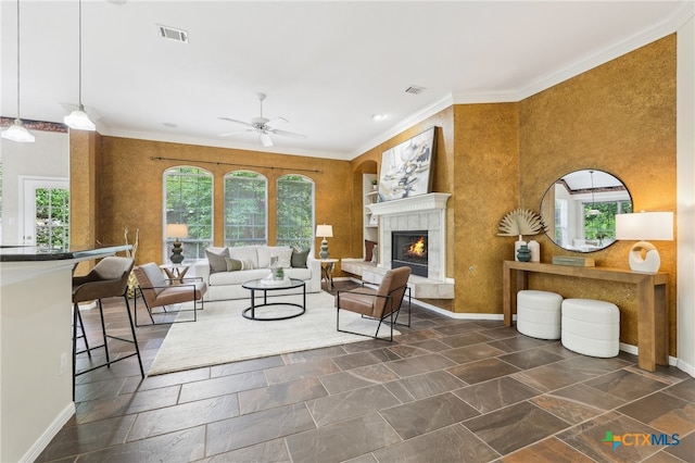 living room with a ceiling fan, ornamental molding, a warm lit fireplace, and baseboards
