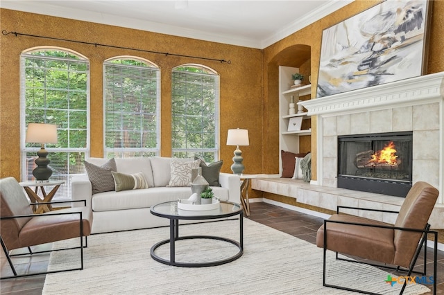 living room with a tile fireplace, crown molding, and built in features