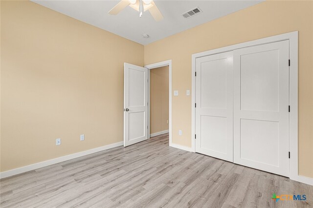 unfurnished bedroom featuring ceiling fan, a closet, and light wood-type flooring