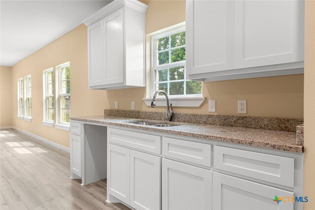 kitchen featuring light wood-type flooring, sink, a healthy amount of sunlight, and white cabinets