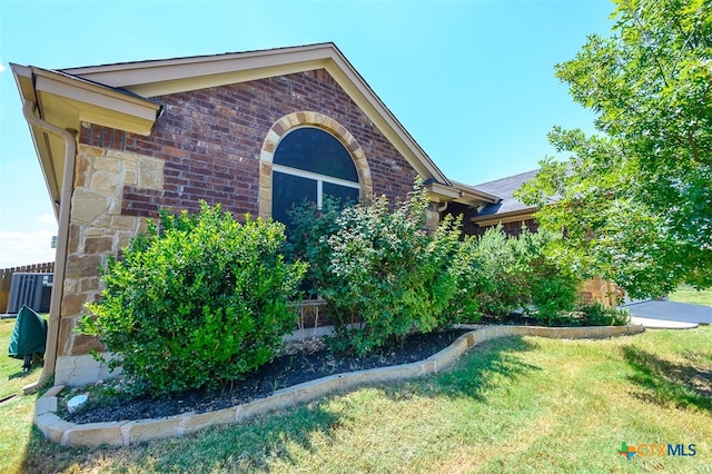 view of property exterior with central AC unit and a yard