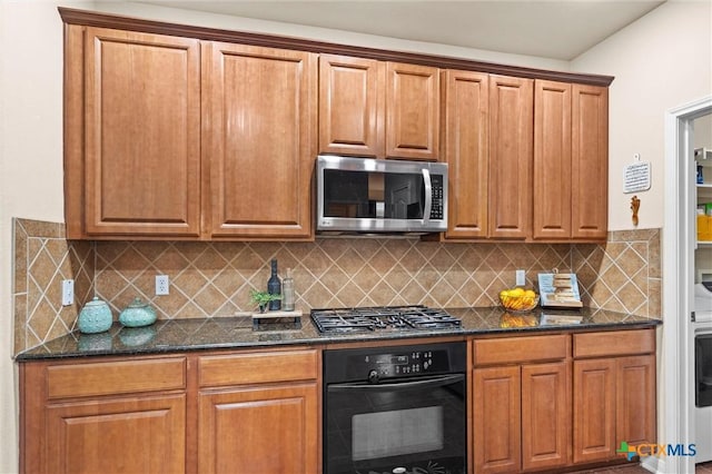 kitchen with black oven, stainless steel microwave, gas cooktop, and dark stone countertops