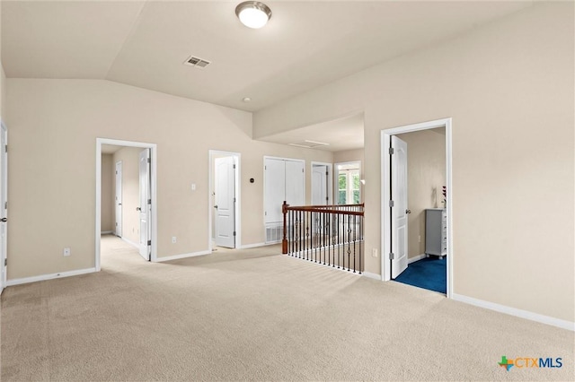 carpeted spare room with vaulted ceiling and baseboards
