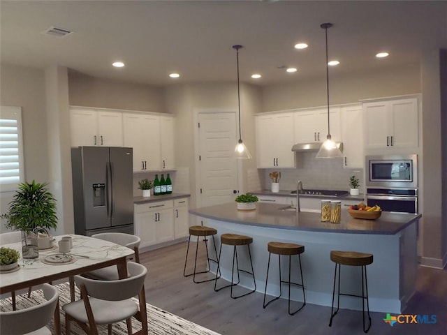791 Hazy Hills Loop, Dripping Springs, TX 78620 - kitchen featuring stainless steel appliances, wood finished floors, tasteful backsplash, dark countertops, and a breakfast bar area