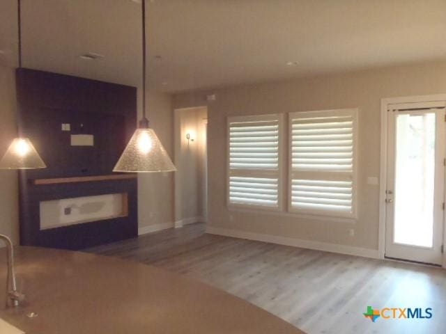 791 Hazy Hills Loop, Dripping Springs, TX 78620 - unfurnished living room featuring wood finished floors and plenty of natural light
