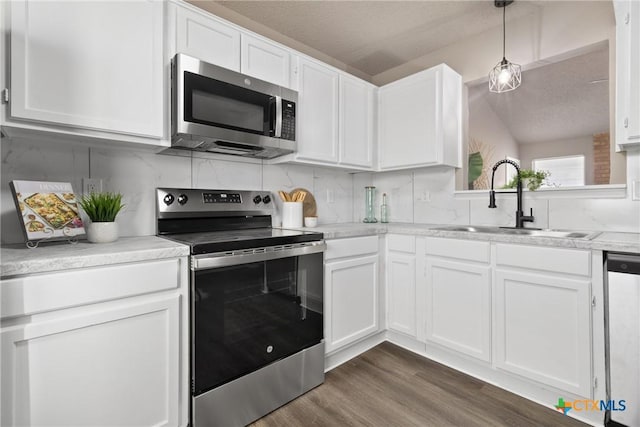 kitchen featuring white cabinetry, sink, dark hardwood / wood-style flooring, hanging light fixtures, and stainless steel appliances