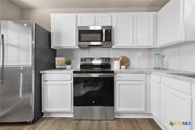 kitchen with white cabinetry, decorative backsplash, and stainless steel appliances