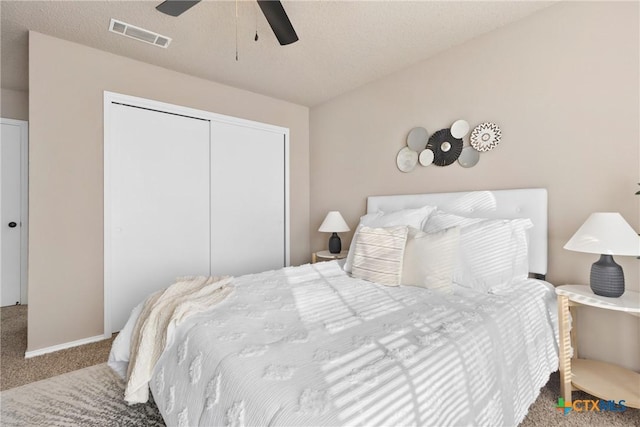 carpeted bedroom featuring ceiling fan, a closet, and a textured ceiling