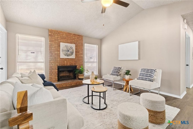 living room with a fireplace, lofted ceiling, hardwood / wood-style flooring, ceiling fan, and a textured ceiling