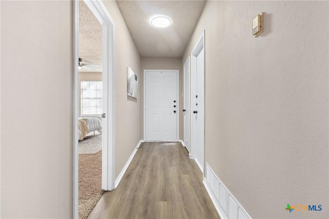 hallway featuring wood-type flooring and a textured ceiling