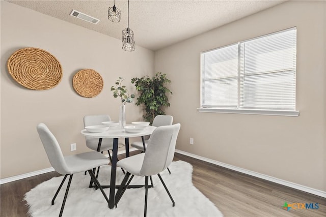 dining space with hardwood / wood-style flooring and a textured ceiling