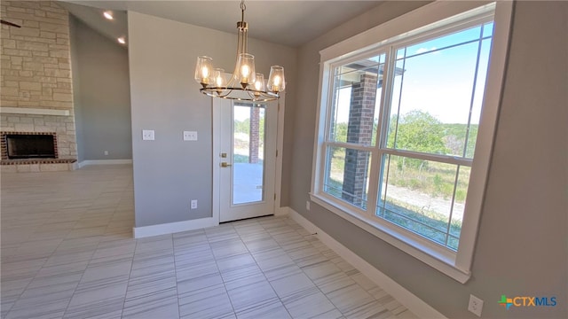 doorway featuring a fireplace, plenty of natural light, light tile patterned floors, and an inviting chandelier