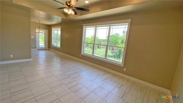 empty room featuring ceiling fan with notable chandelier and a healthy amount of sunlight