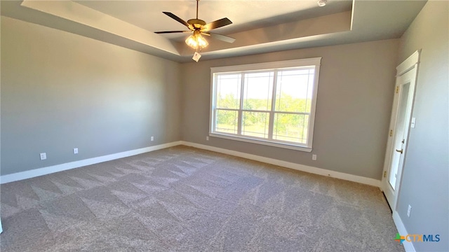 carpeted spare room featuring ceiling fan and a raised ceiling