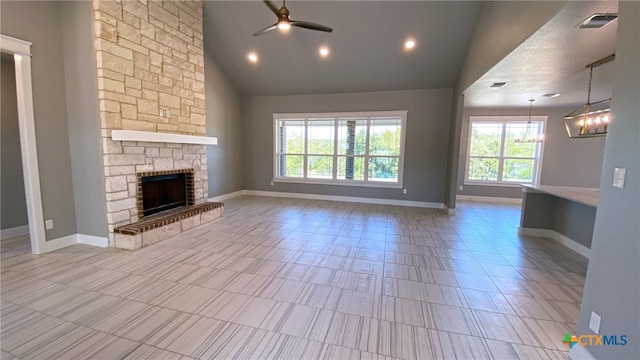 unfurnished living room with a stone fireplace, high vaulted ceiling, and ceiling fan with notable chandelier