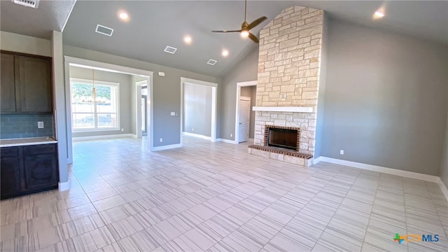 unfurnished living room with a fireplace, ceiling fan with notable chandelier, and high vaulted ceiling