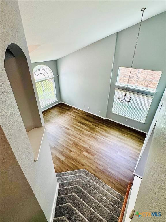 3413 Malmaison Rd, Killeen, TX 76542 - unfurnished living room featuring wood finished floors, stairway, a textured wall, and arched walkways
