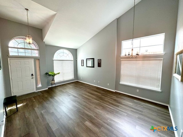 entrance foyer with high vaulted ceiling, an inviting chandelier, and dark hardwood / wood-style floors