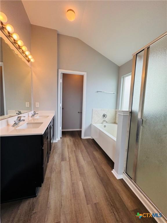 3413 Malmaison Rd, Killeen, TX 76542 - bathroom with wood finished floors, vaulted ceiling, a bath, double vanity, and a stall shower