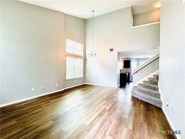 3413 Malmaison Rd, Killeen, TX 76542 - unfurnished living room with a high ceiling, a chandelier, wood finished floors, and baseboards