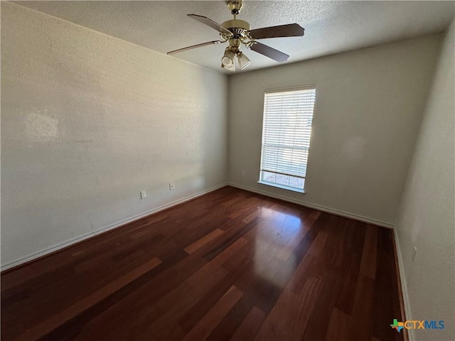 spare room with a textured ceiling, ceiling fan, and dark wood-type flooring