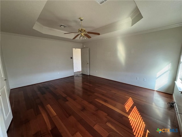 empty room with a tray ceiling, ceiling fan, dark hardwood / wood-style floors, and ornamental molding