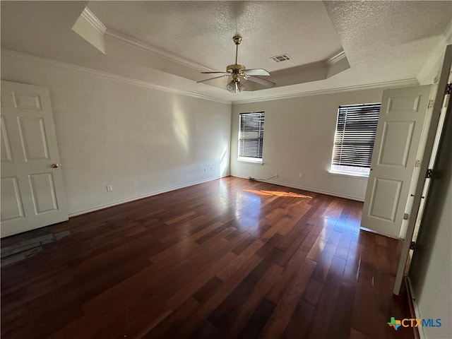 empty room featuring ceiling fan, dark hardwood / wood-style flooring, crown molding, a textured ceiling, and a tray ceiling