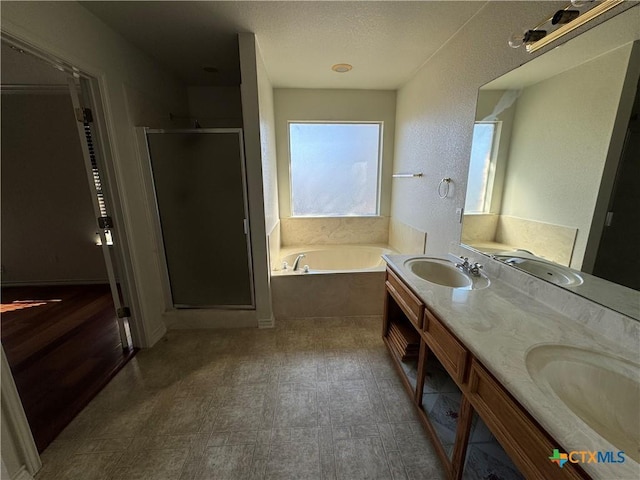 bathroom featuring a textured ceiling, vanity, and shower with separate bathtub