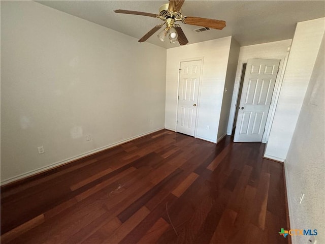 unfurnished bedroom featuring ceiling fan and dark hardwood / wood-style flooring